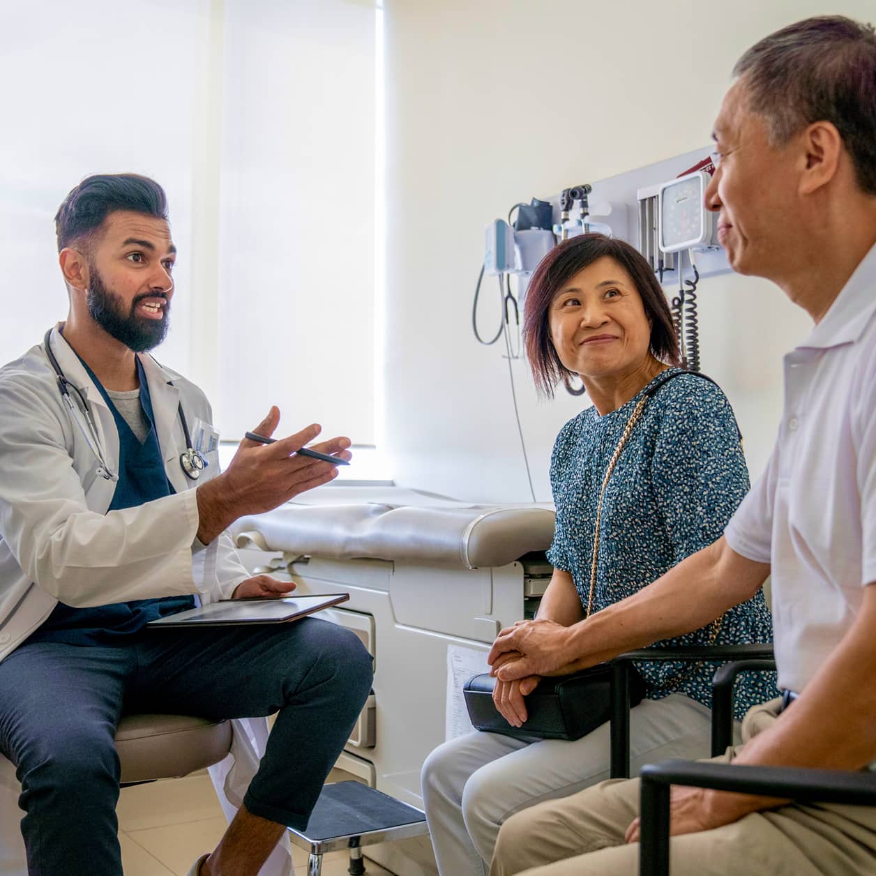 A practitioner in conversation with a couple in an exam room.