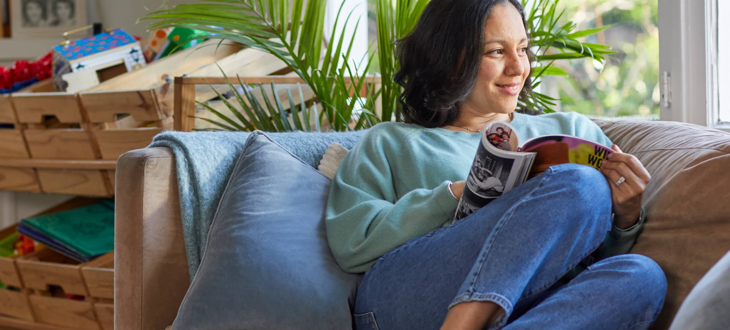 A person reading a magazine on their sofa.