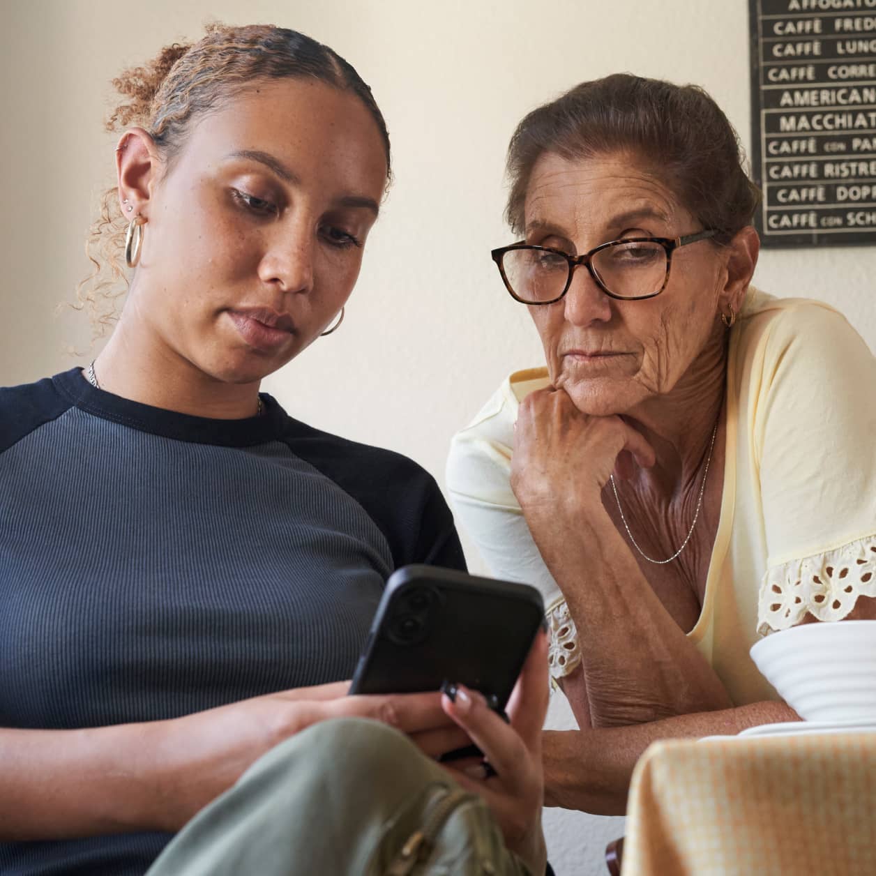 An older parent and young adult checking a prescription on a cell phone.