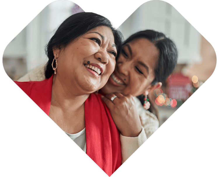 A mother and adult daughter smiling together.
