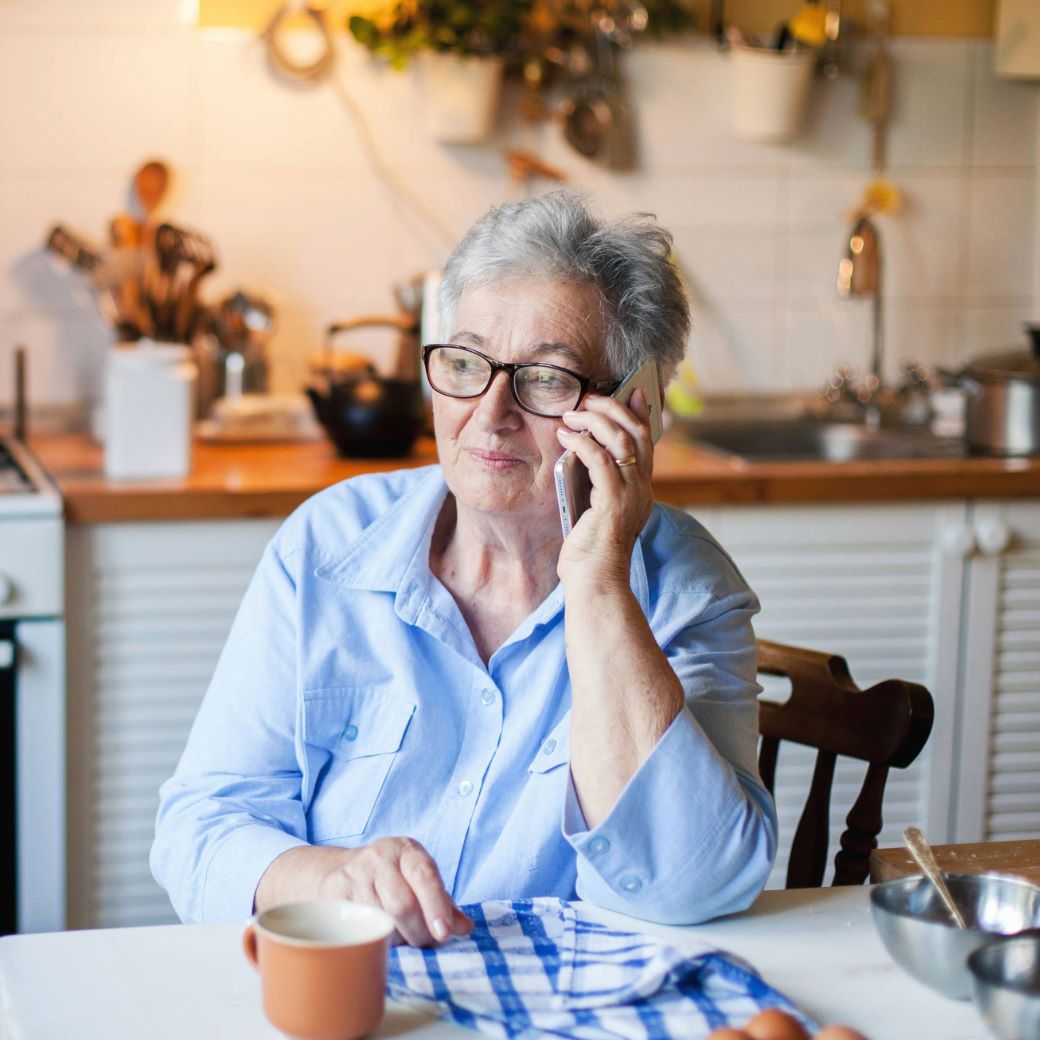 Person in light blue shirt sitting at kitchen table with coffee mug and dish towel.