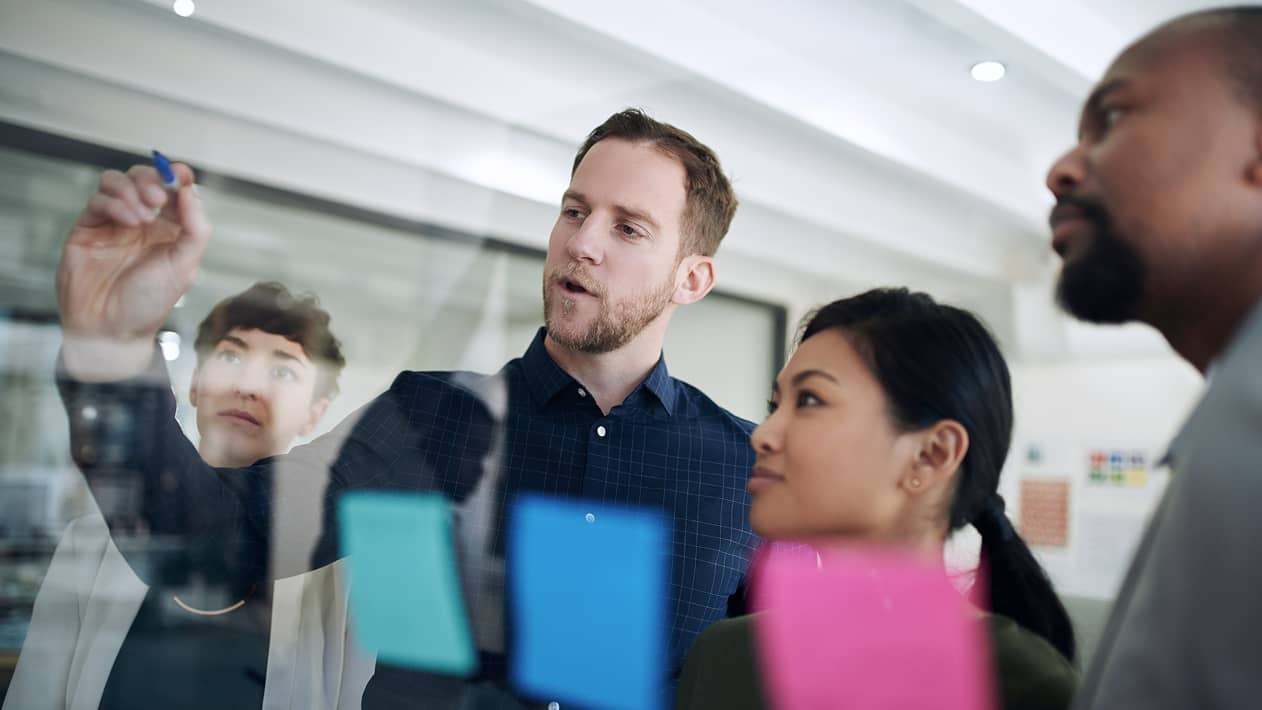 Coworkers working together at a wall with notes.