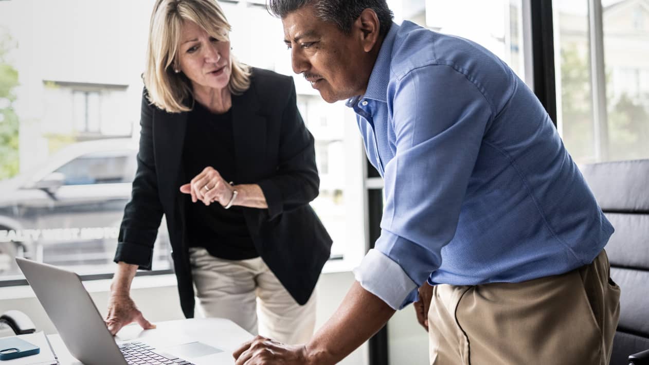 Two colleagues conferring as they look at a laptop screen