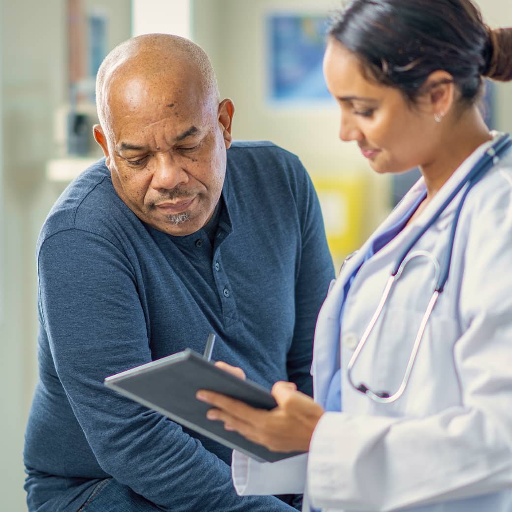 A practitioner showing something on a tablet screen to a patient.