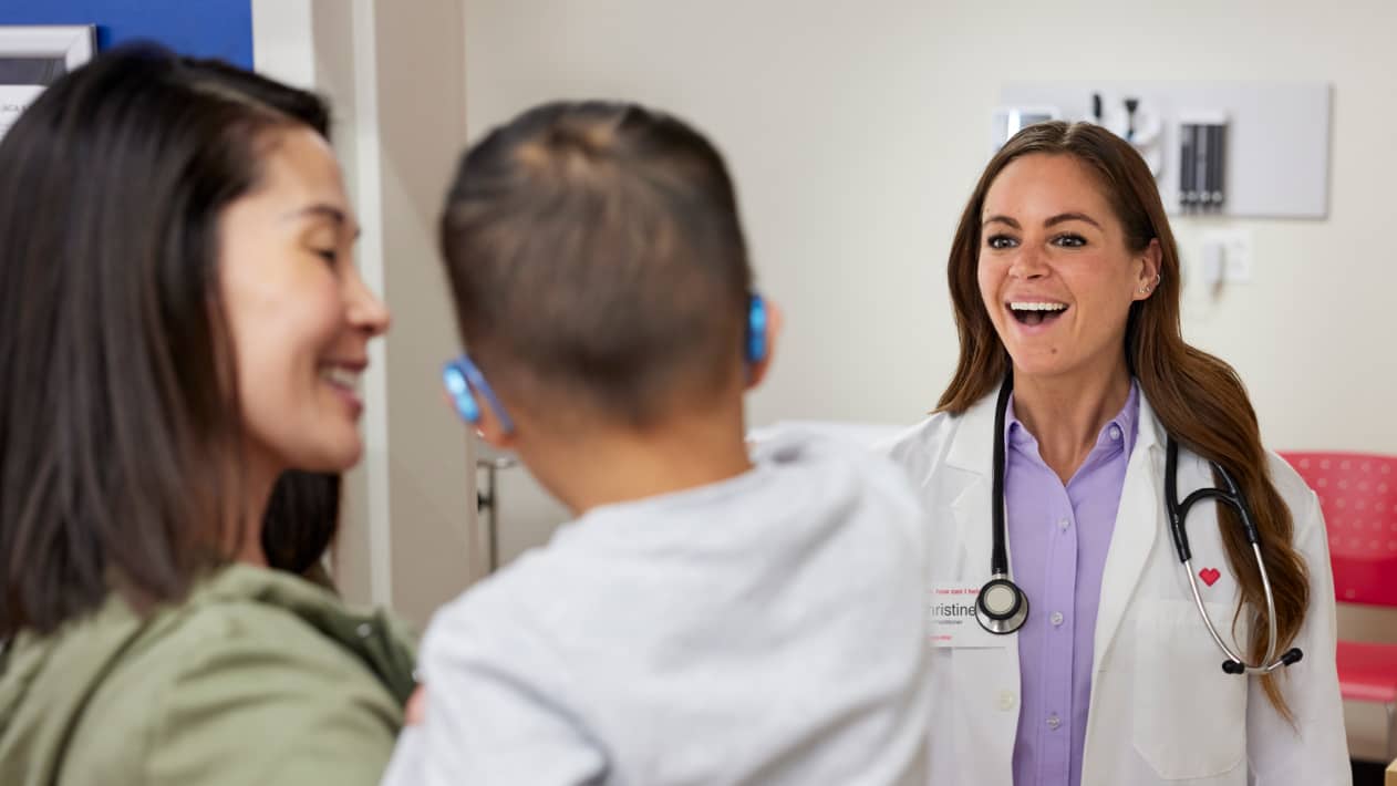 A parent holding their small child, facing a smiling CVS practitioner