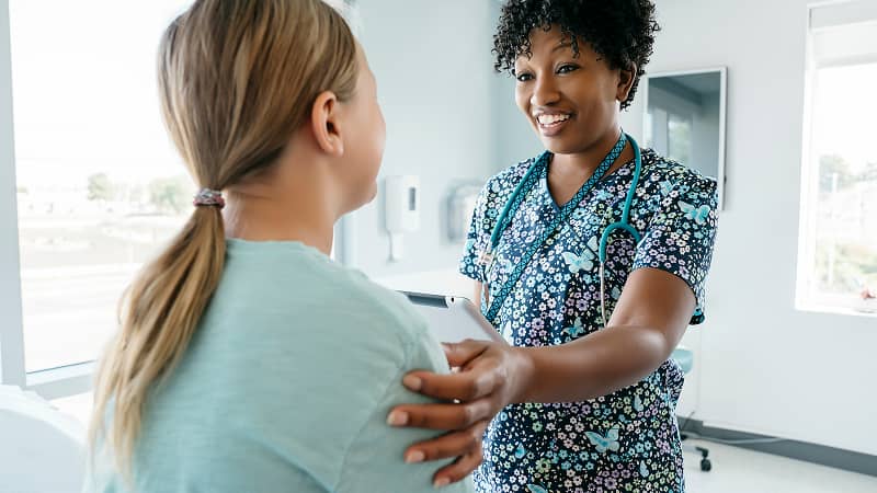 A health care provider in conversation with a patient in an exam room