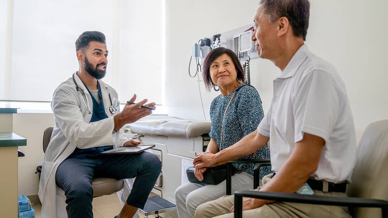 A couple in conversation with a practitioner in an exam room.