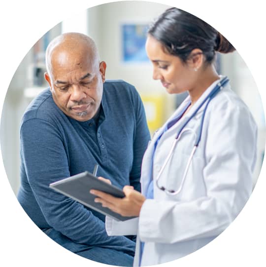 A practitioner wearing a stethoscope shows a tablet screen to a patient