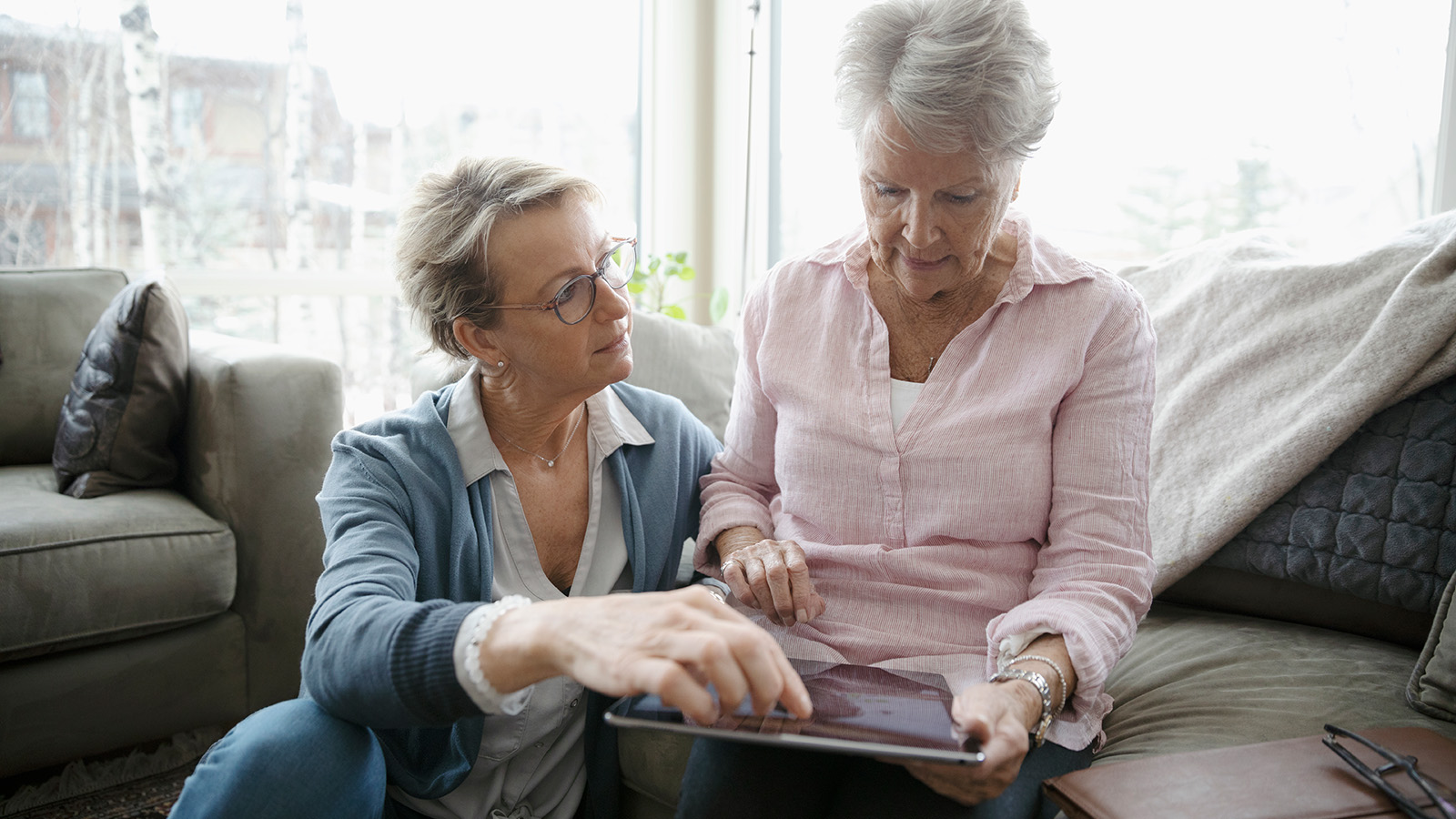 Two older women reviewing information on a tablet.