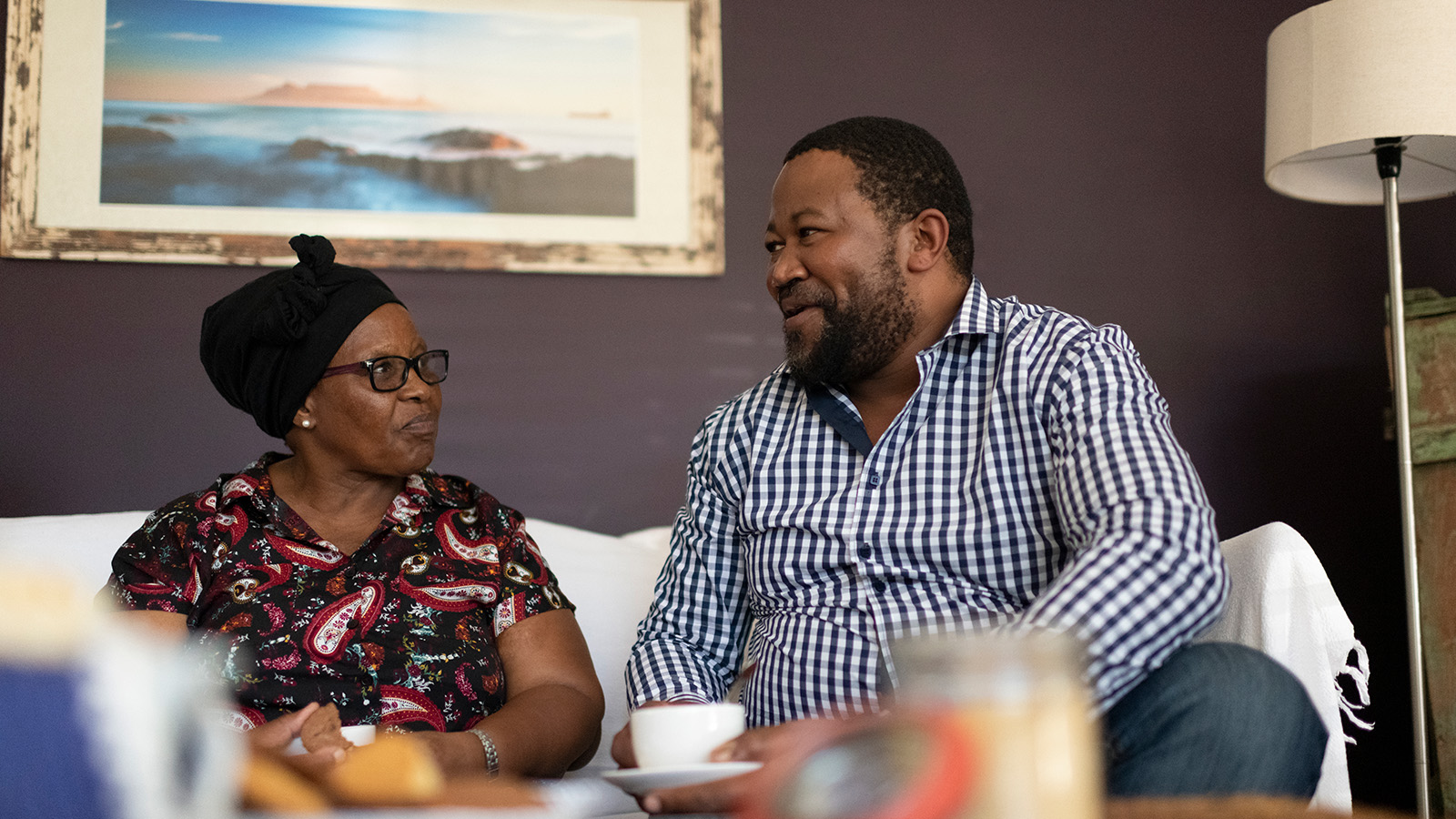 Two people engaged in conversation while sitting on a couch.