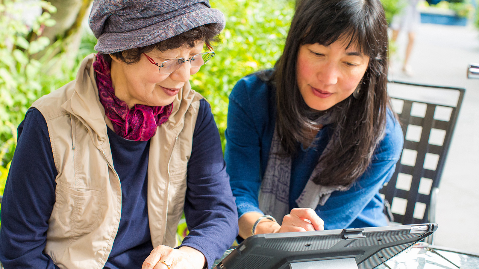 Individual reading a tablet while seated at a table.