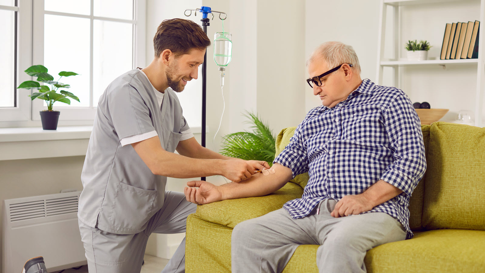 Healthcare professional administering IV treatment to a patient on a couch.