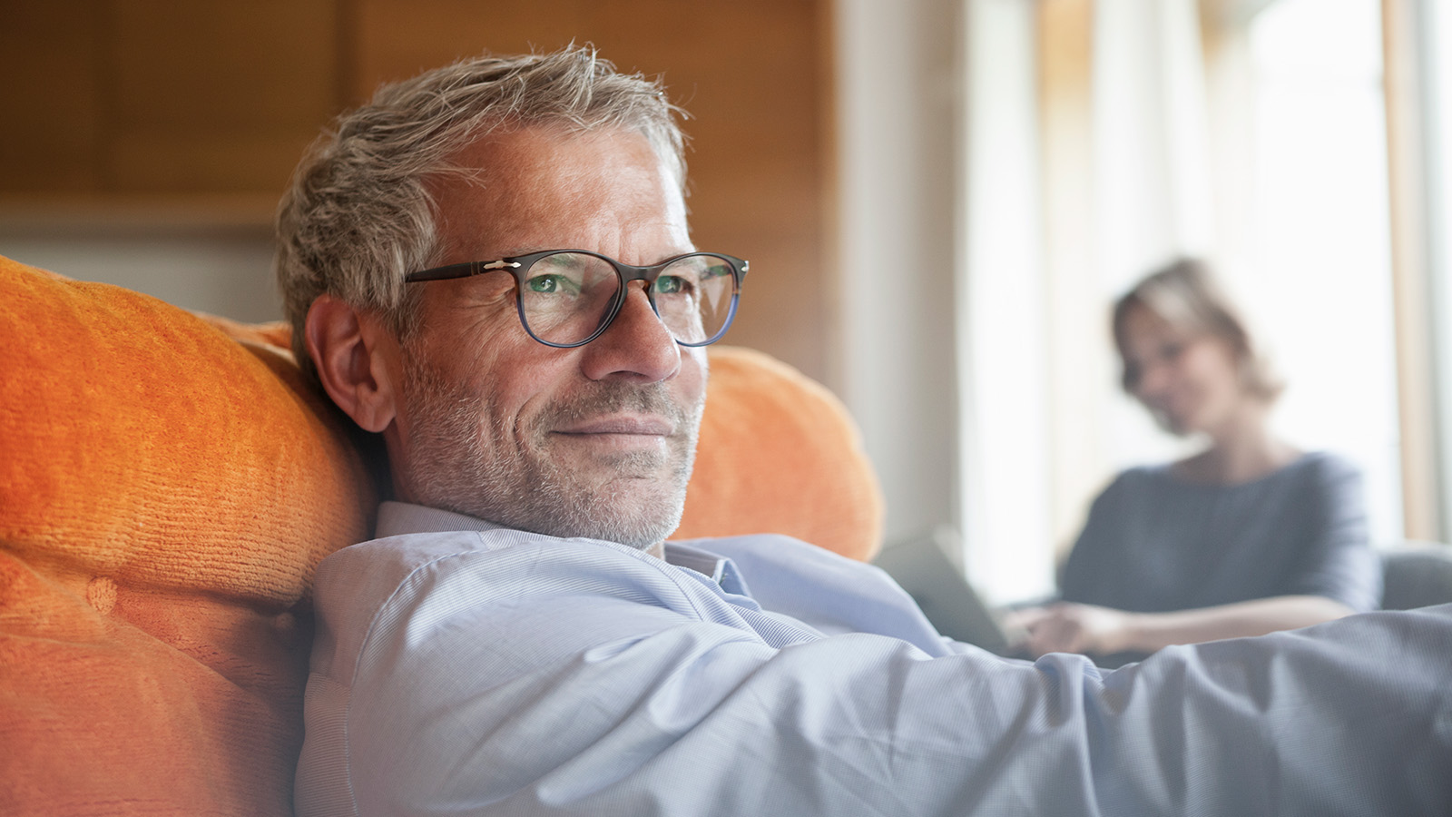 A man relaxing on a couch with a woman in the background