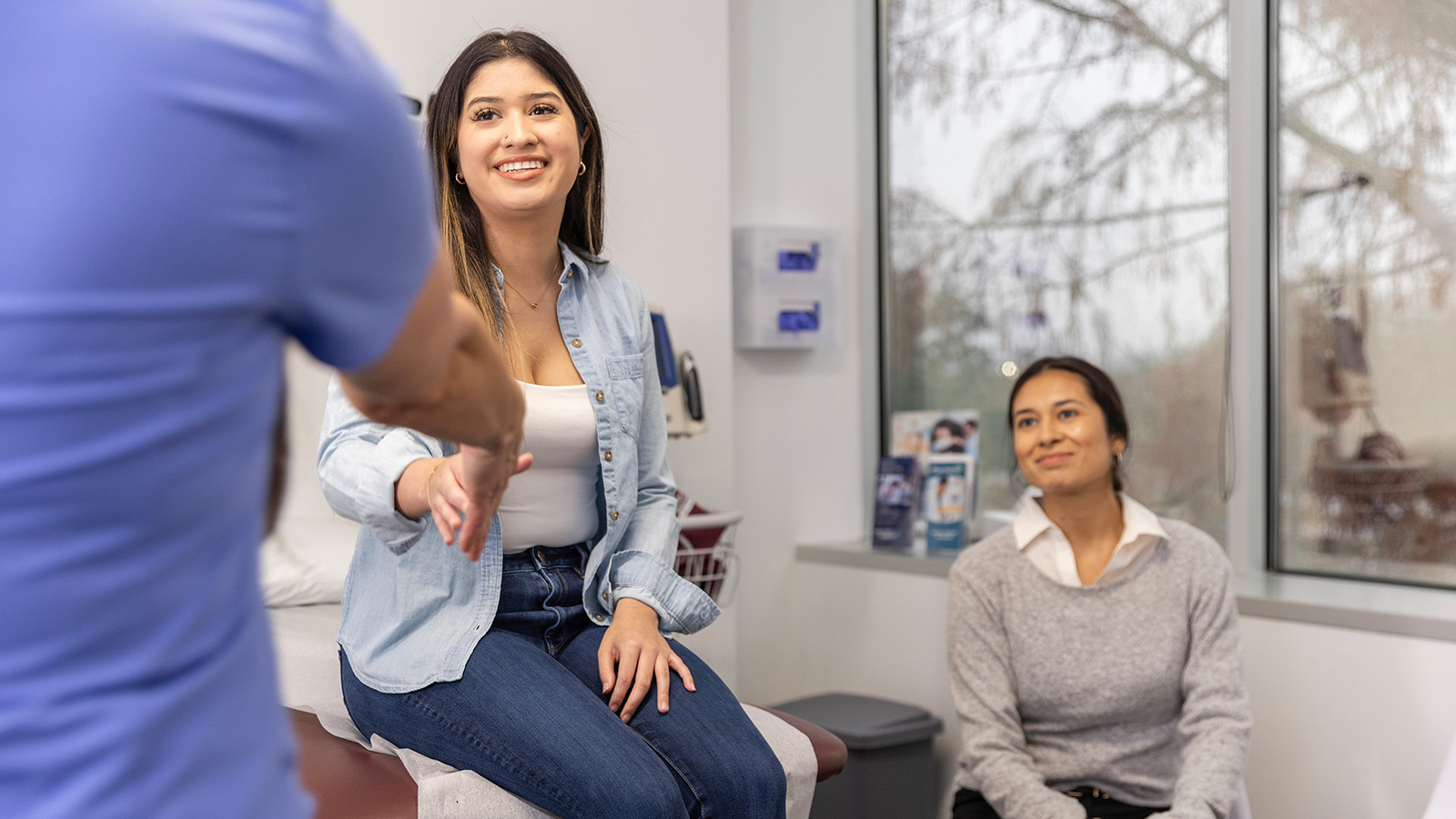 A medical professional interacting with two patients in an office