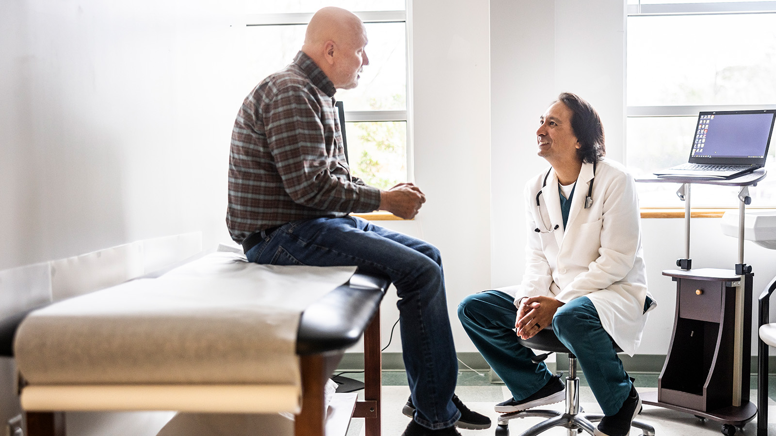 A doctor and a patient engage in conversation in a medical office, with a focus on the patient’s concerns.