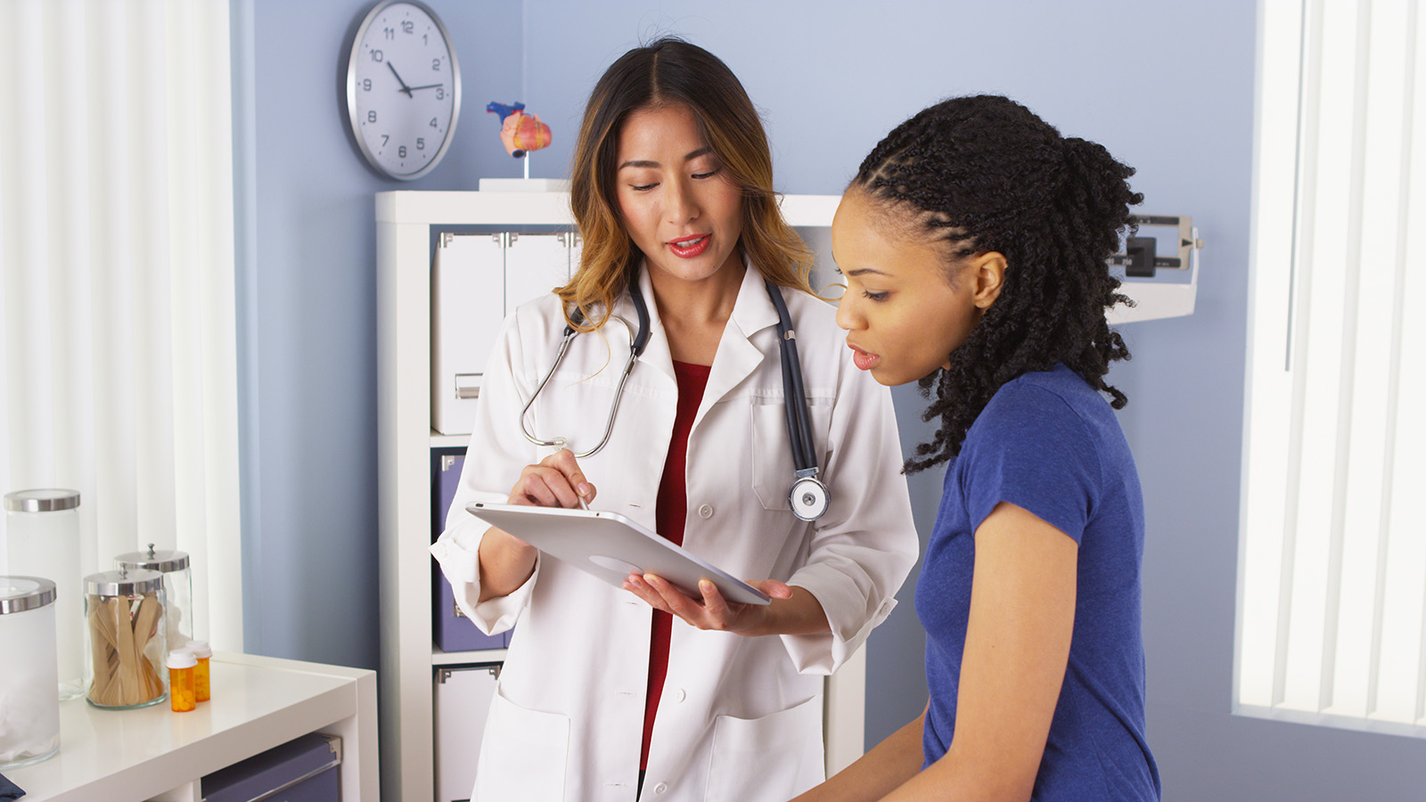 A doctor discusses information with a patient in a medical office, emphasizing communication and care in a healthcare environment.