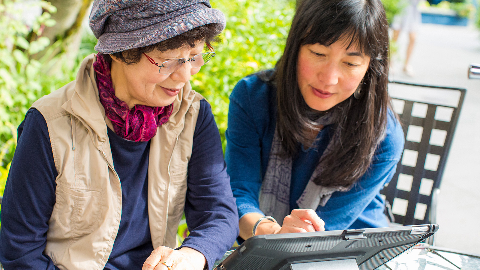 Two women looking at a tablet together in a garden setting
