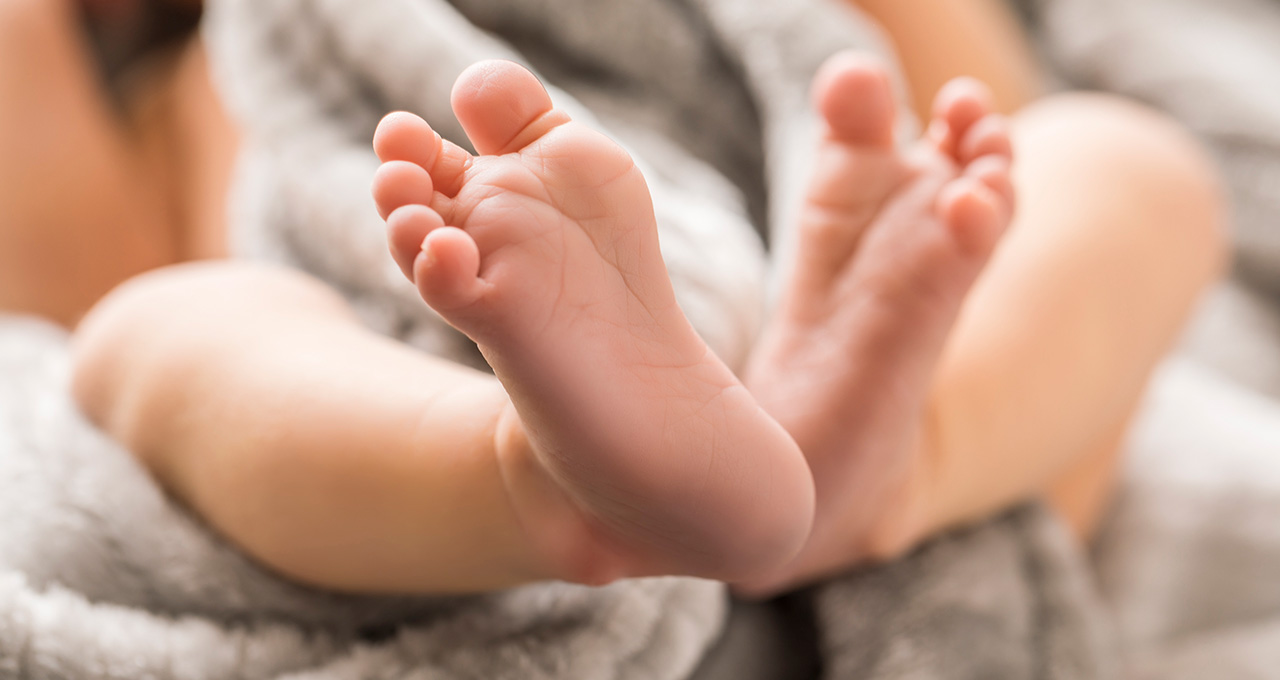 Close-up of two small feet resting on a soft blanket