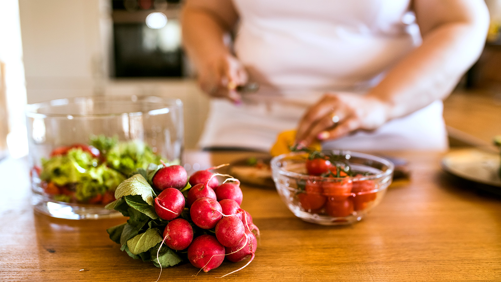 A woman is chopping vegetables in a kitchen, preparing a fresh meal