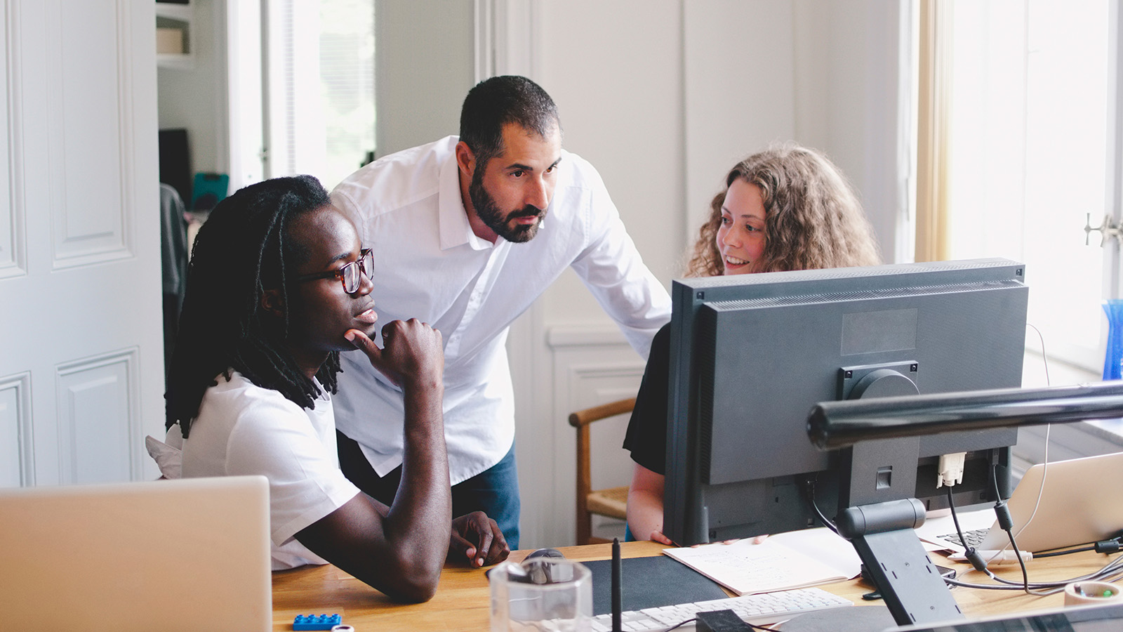 Three colleagues are discussing a project while seated at a table