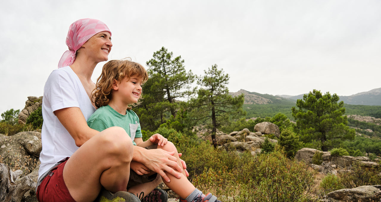 Adult and child sitting together outdoors, enjoying nature.