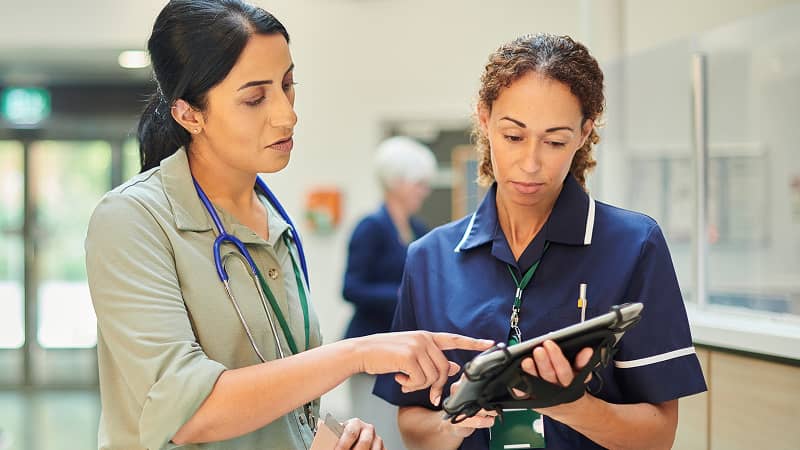 Two practitioners sharing information on a tablet.