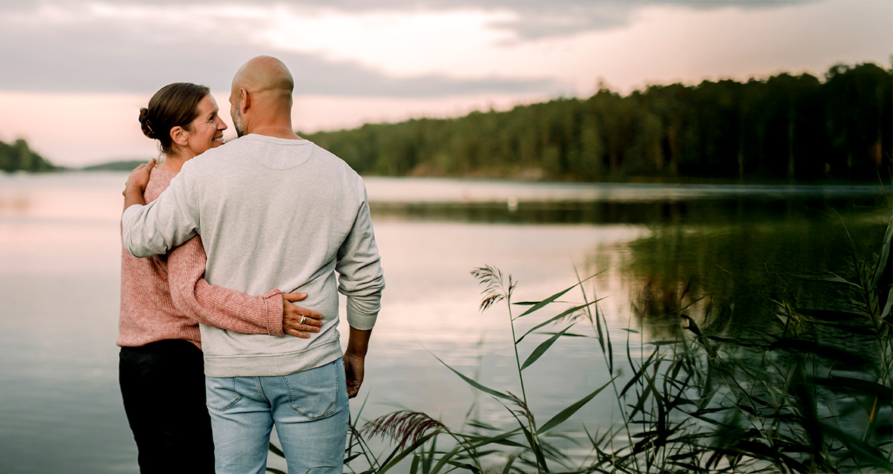 A couple embracing by a lake at sunset