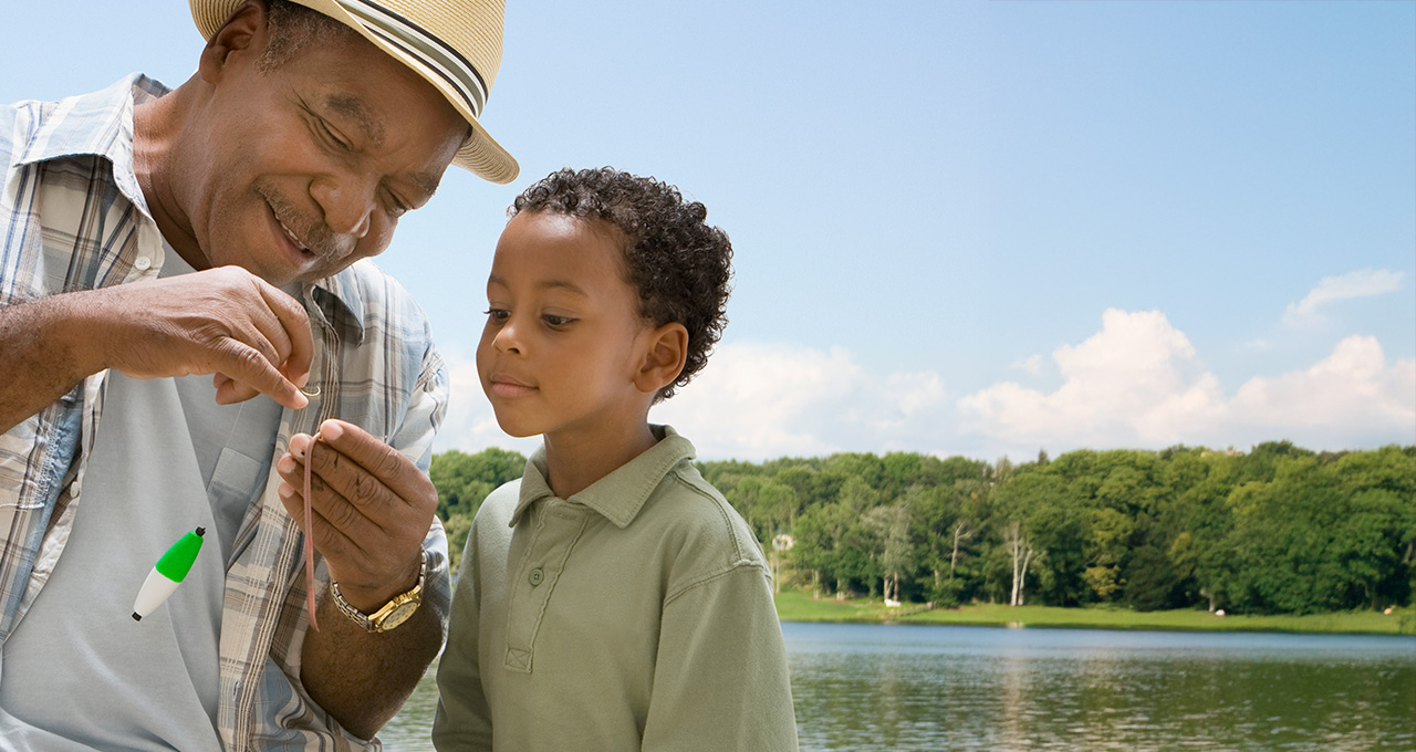 An adult teaching a child about fishing by a lake