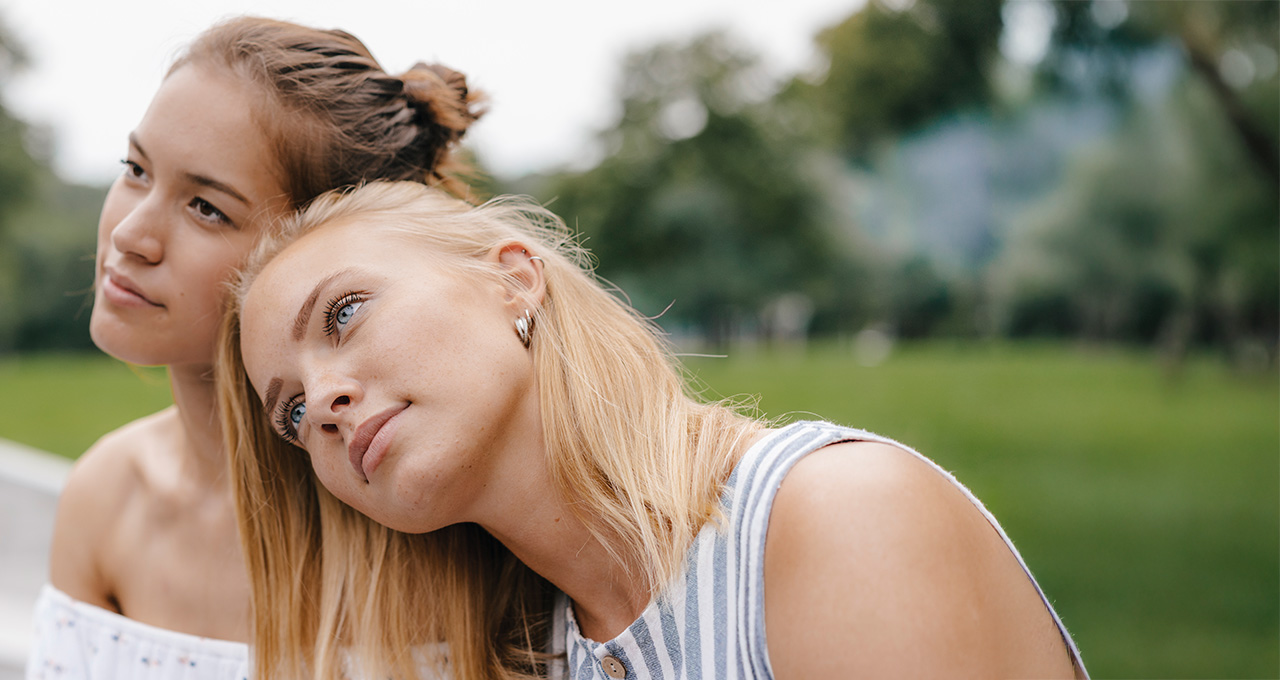 Two women closely leaning together outdoors