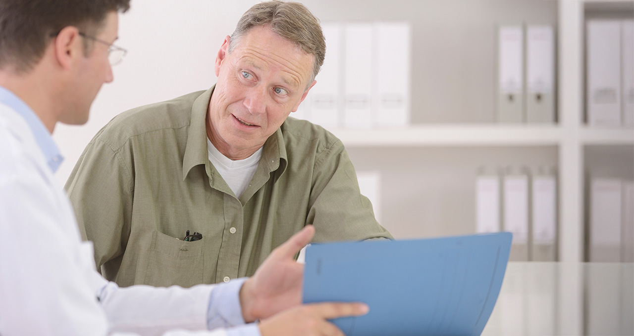 A patient listens attentively to a doctor discussing information, with a clean, modern medical office in the background.